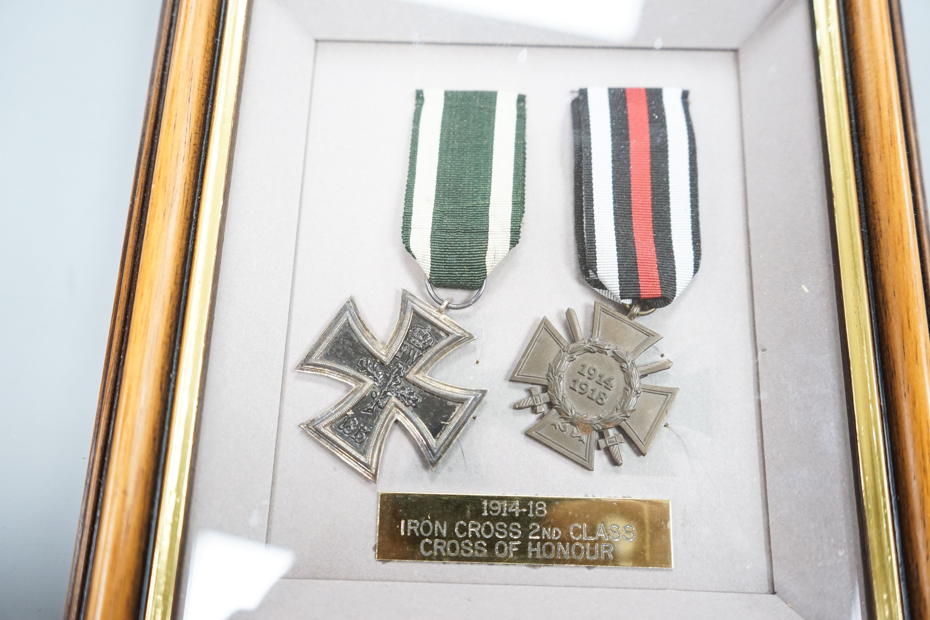 A German WWII Mother's Cross, rare unfinished, framed WWI Iron Cross and Cross of Honour and two miniature photographic booklets.